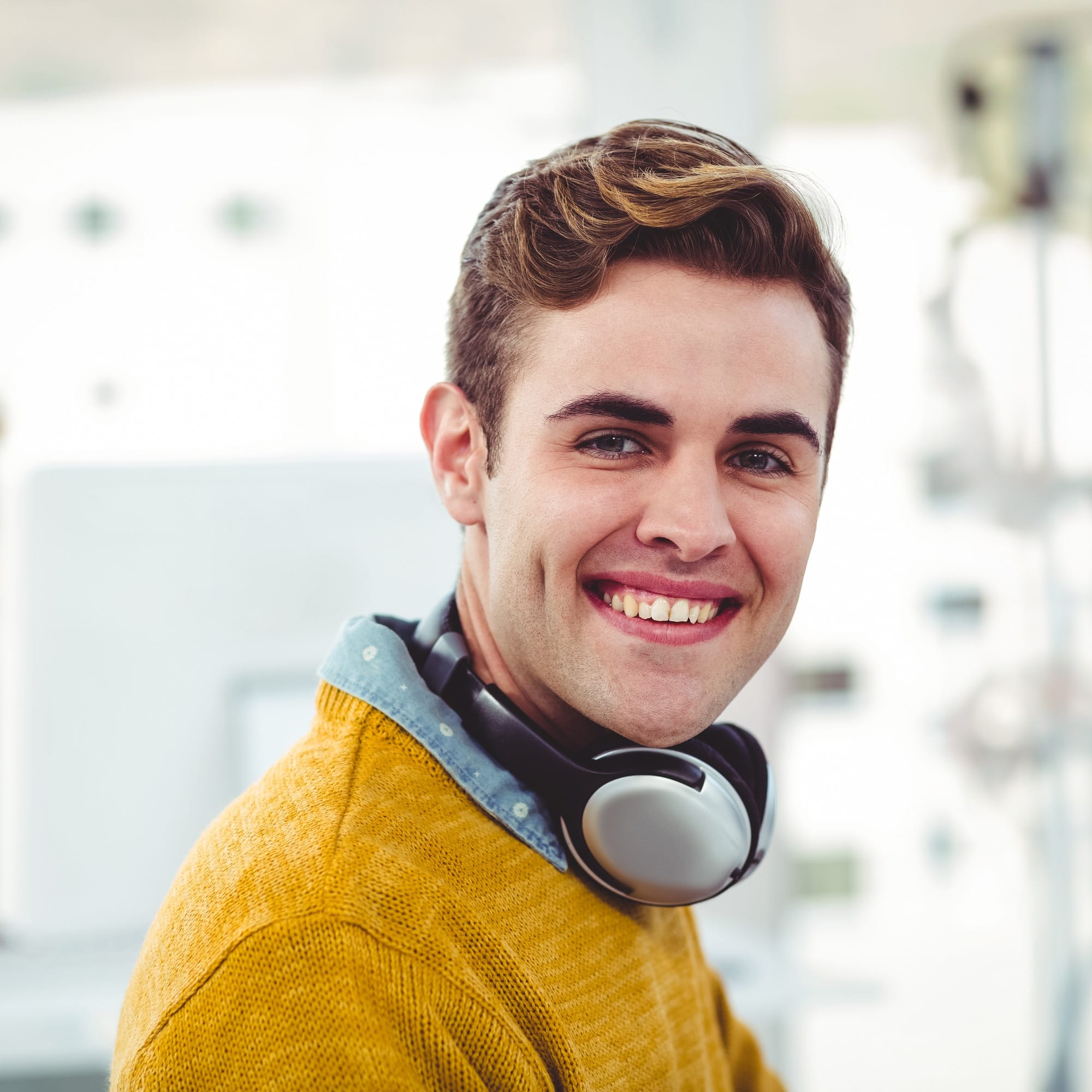 Smiling young man with headphones working in modern office environment
